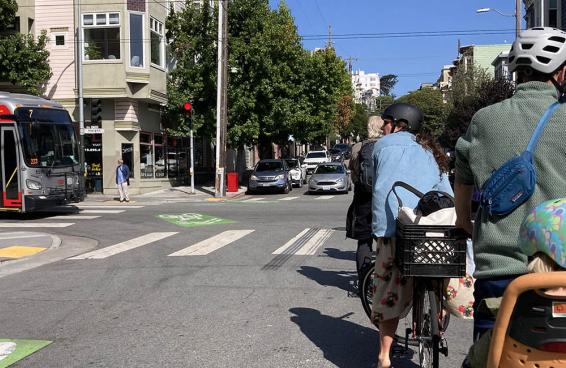 Cyclists wait for a Muni bus to pass by.
