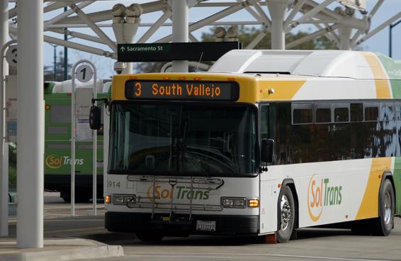 A SolTrans bus sits at a bus stop at the Vallejo Transit Center on a sunny day.
