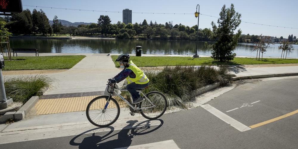 A cyclist rides on a separated bike path along Lake Merrit.