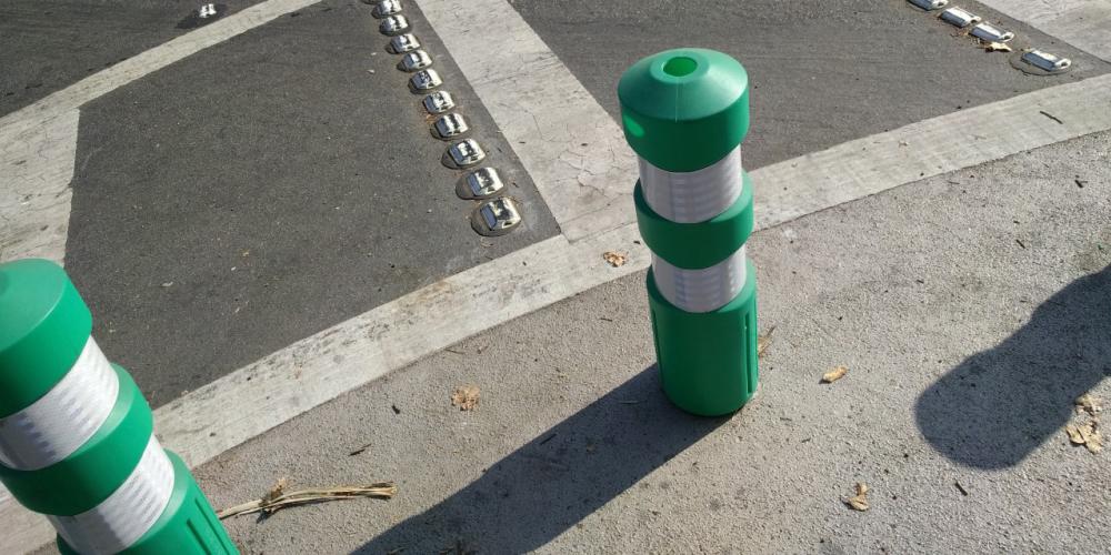 Green bollards at a crosswalk to prevent vehicles from driving into protected areas.