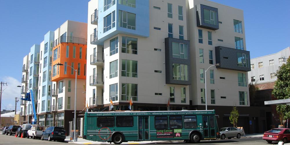 An AC transit bus drives by an apartment building in Oakland.