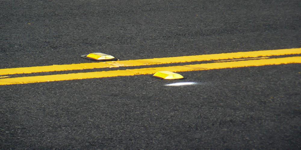 A well-paved street marked with a double yellow line and reflectors.
