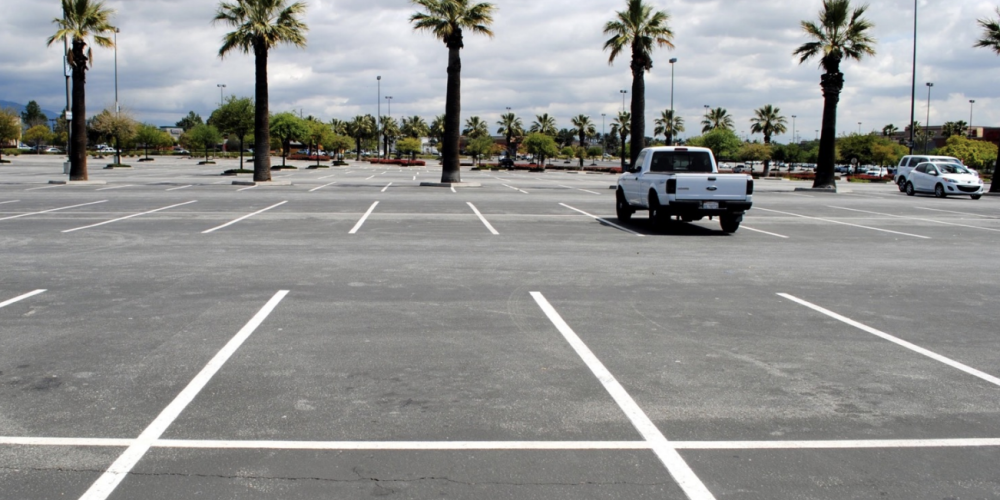 car parked in an empty parking lot with palm trees