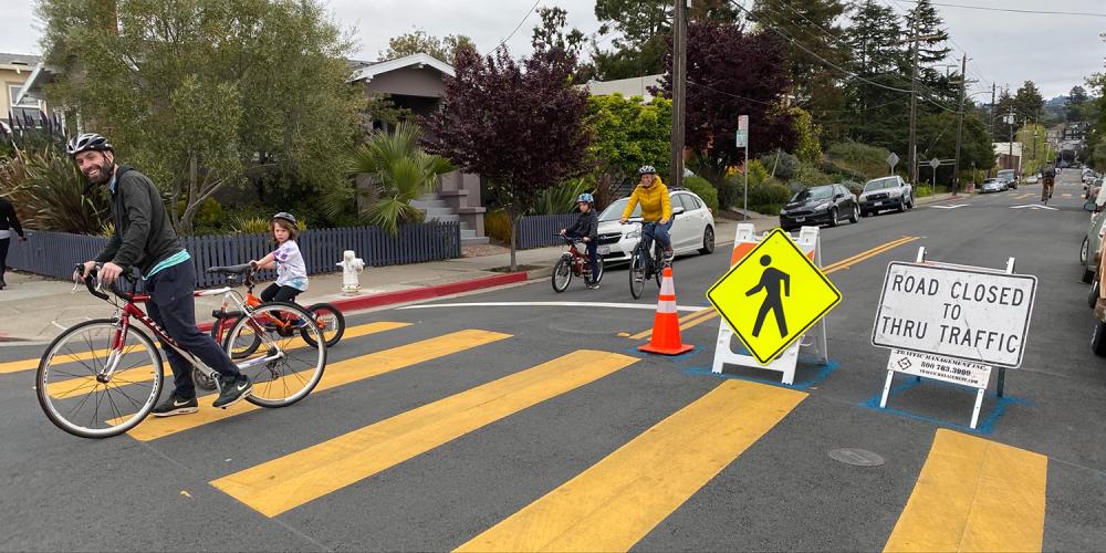 Adults and children riding bicycles on a closed Slow Street in Oakland.