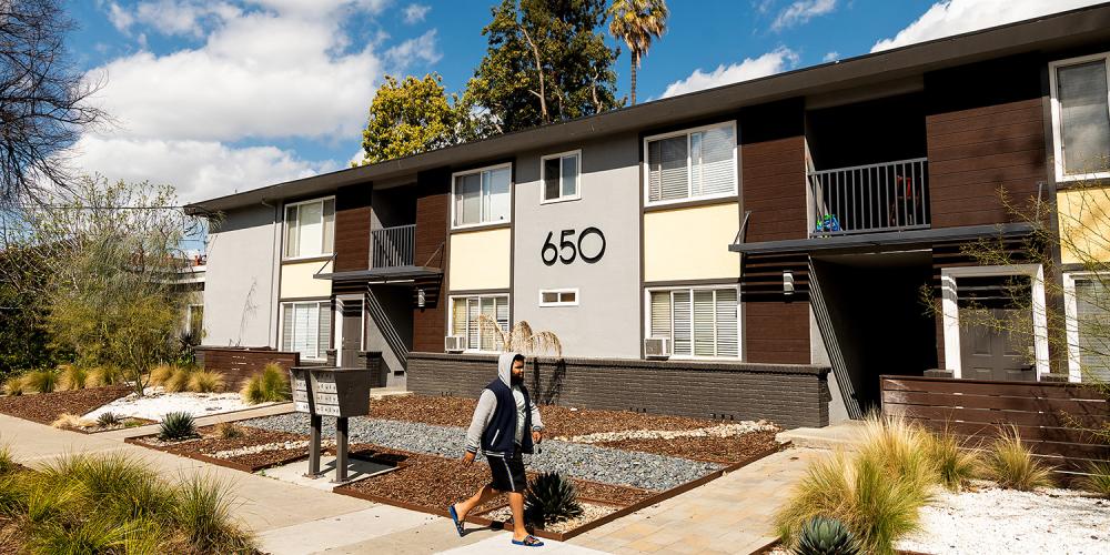 A person walking on a sidewalk in front of townhomes.