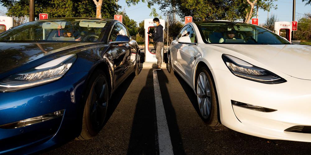Tesla electric vehicles parked side-by-side at a charging station.
