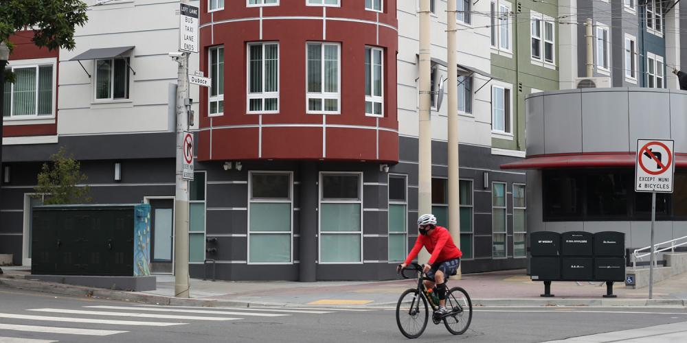 A cyclist rides by an affordable housing apartment building in San Francisco.