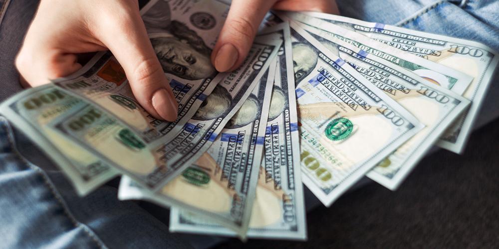 A person holding several U.S. $100 bills.