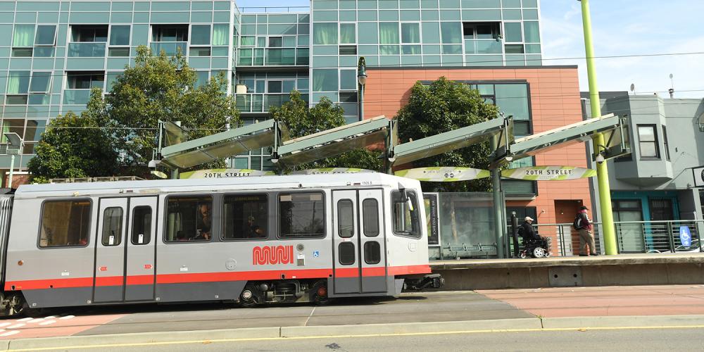 A Muni street car train on Third Street in front of residential buildings in Mission Bay.