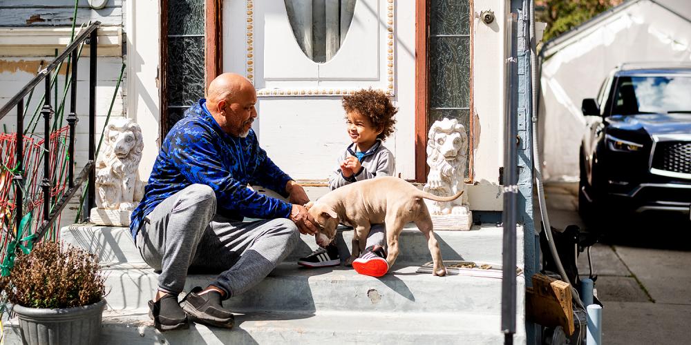 A happy family sits on the steps in front of their home.
