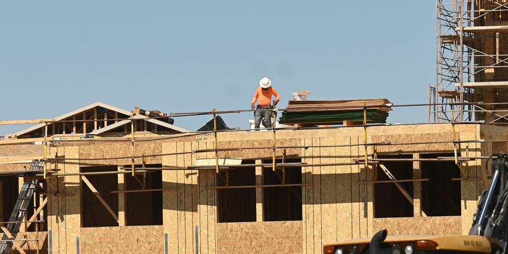 A construction worker stands on the top floor of a home that is under construction.