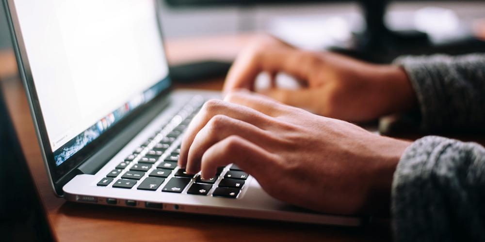A person typing on a laptop computer.
