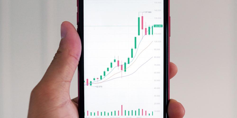 A person holding a cell phone that shows data charts.