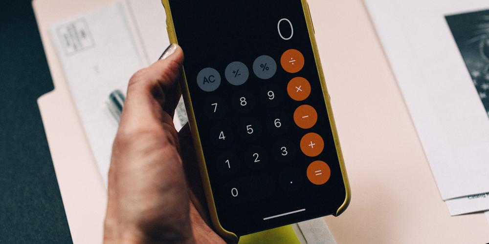 A person using a calculator app on a cellphone.
