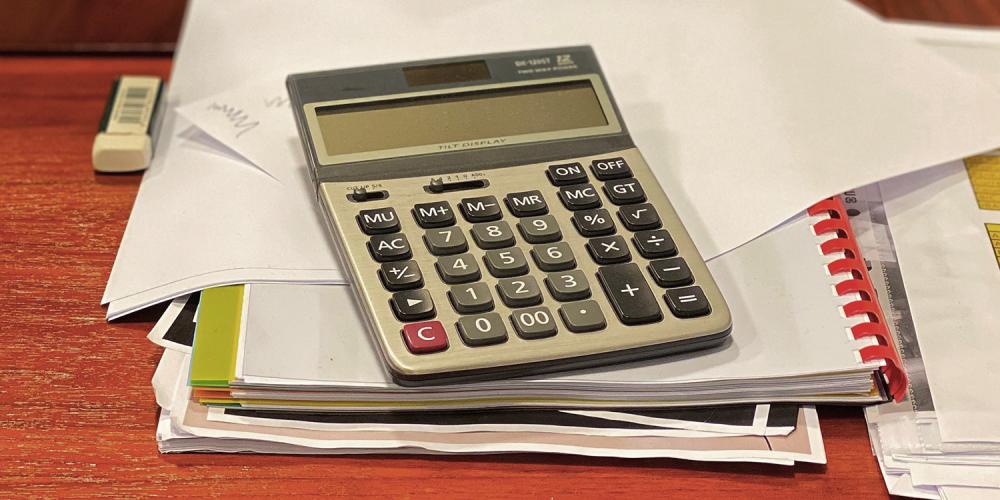 A calculator on top of papers and a notebook.