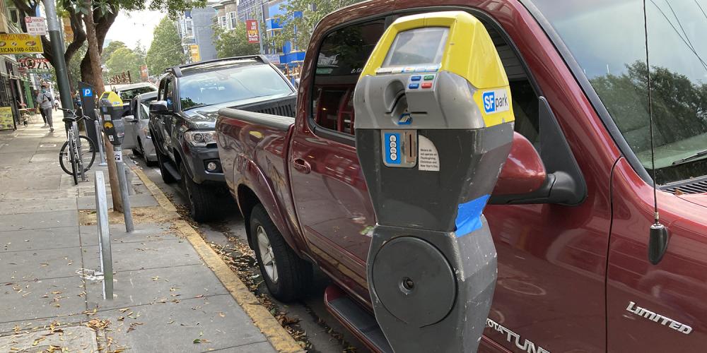 A parking meter and vehicles parked at the curb in San Francisco.