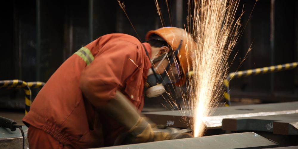 An ironworker grinding metal, with dramatic sparks flying.