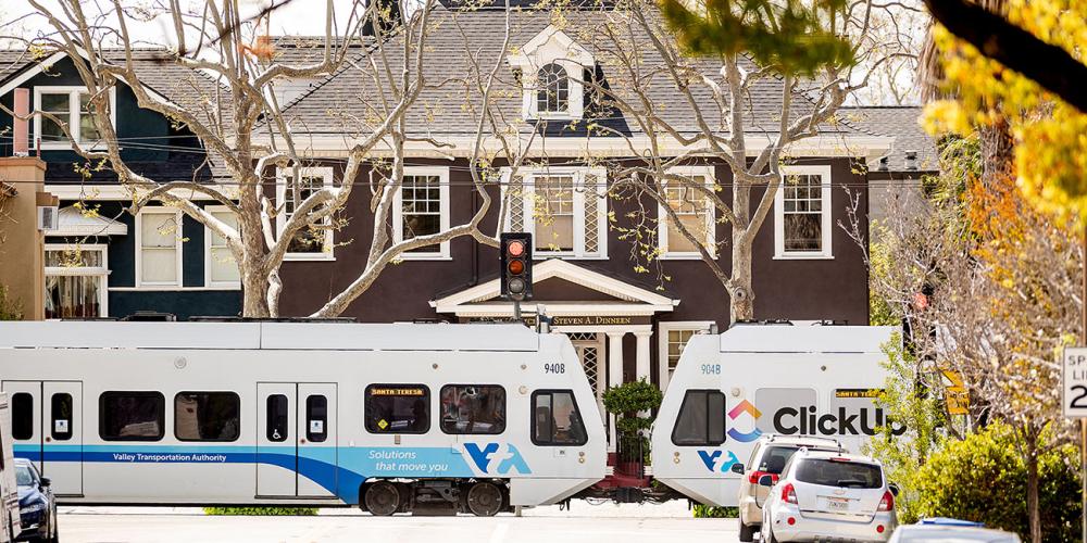 VTA light rail train near a large home on a residential street.