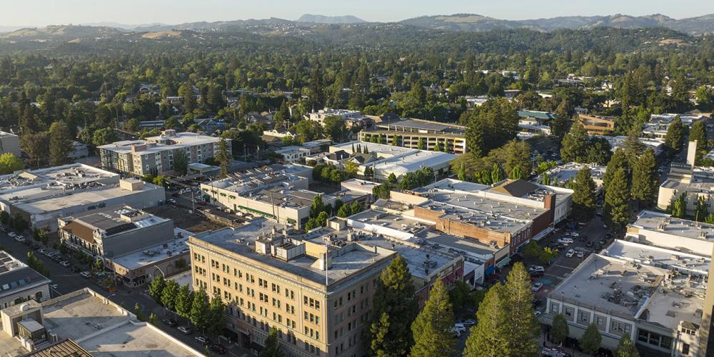 Aerial over apartments in Santa Rosa, with forest in the background.