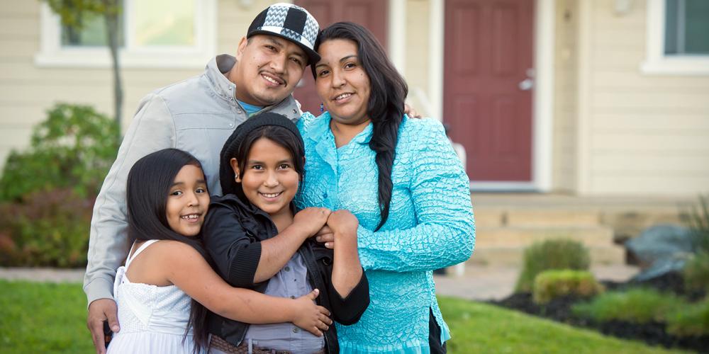 A happy family in front of their home.