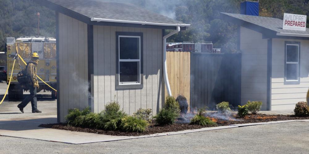 fireman walks toward a smoking house during a wildfire prevention demo