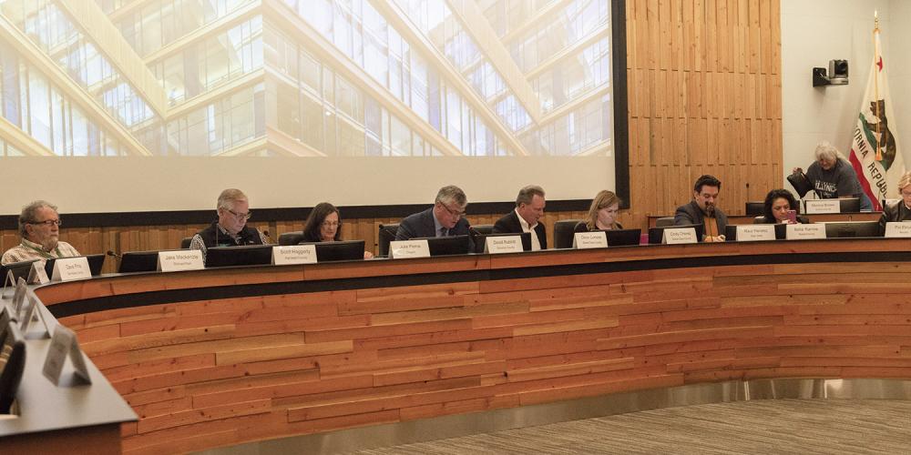 Eight board members sitting at a raised dais at an Executive Board meeting.