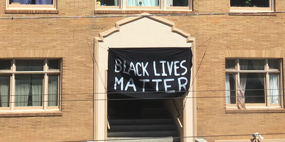 Black Lives Matter banner hangs on the front of a brick building