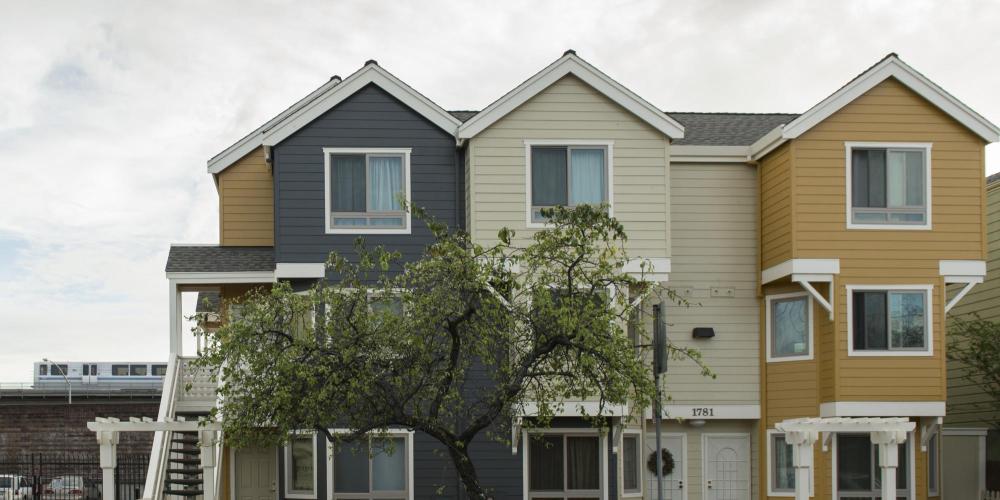 slate blue, cream, and yellow townhomes in front of BART Train and tracks