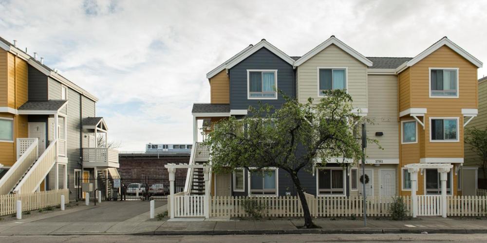 three story housing units side by side with BART train in the background
