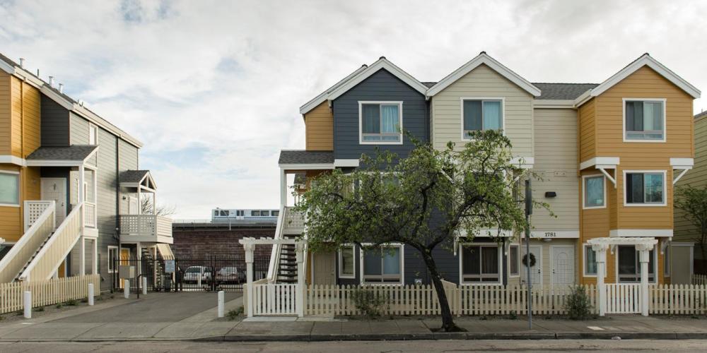 three story housing units side by side with BART train in the background