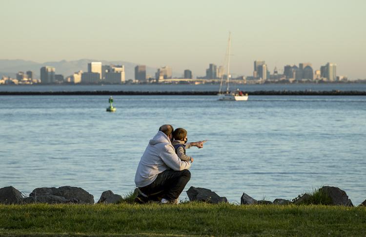 An adult and child pointing at the water in Richmond, California.