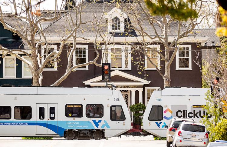 VTA light rail train near a large home on a residential street.