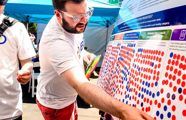 Man places sticker onto foam board to indicate preference for public engagement activity.