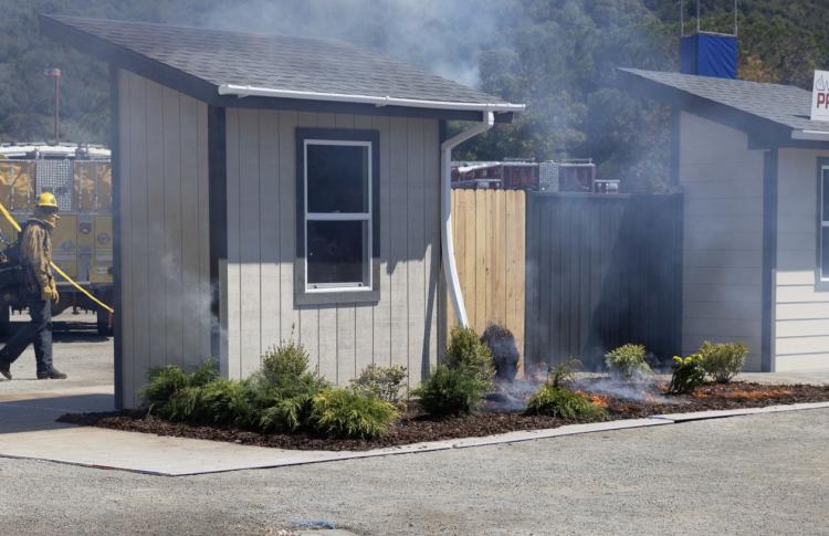 fireman walks toward a smoking house during a wildfire prevention demo