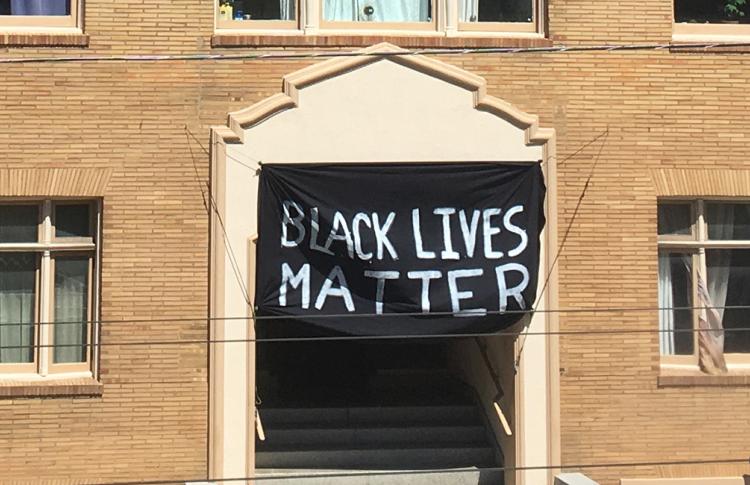 Black Lives Matter banner hangs on the front of a brick building