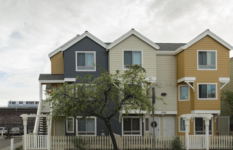 three story housing units side by side with BART train in the background