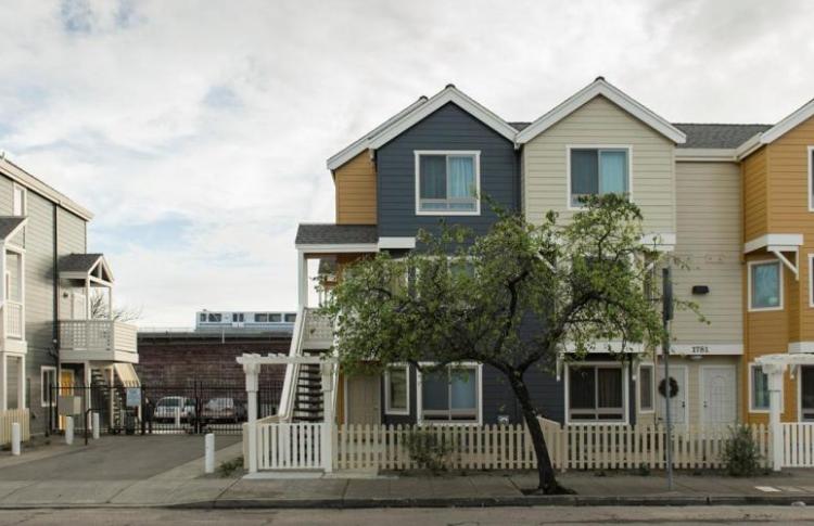 three story housing units side by side with BART train in the background